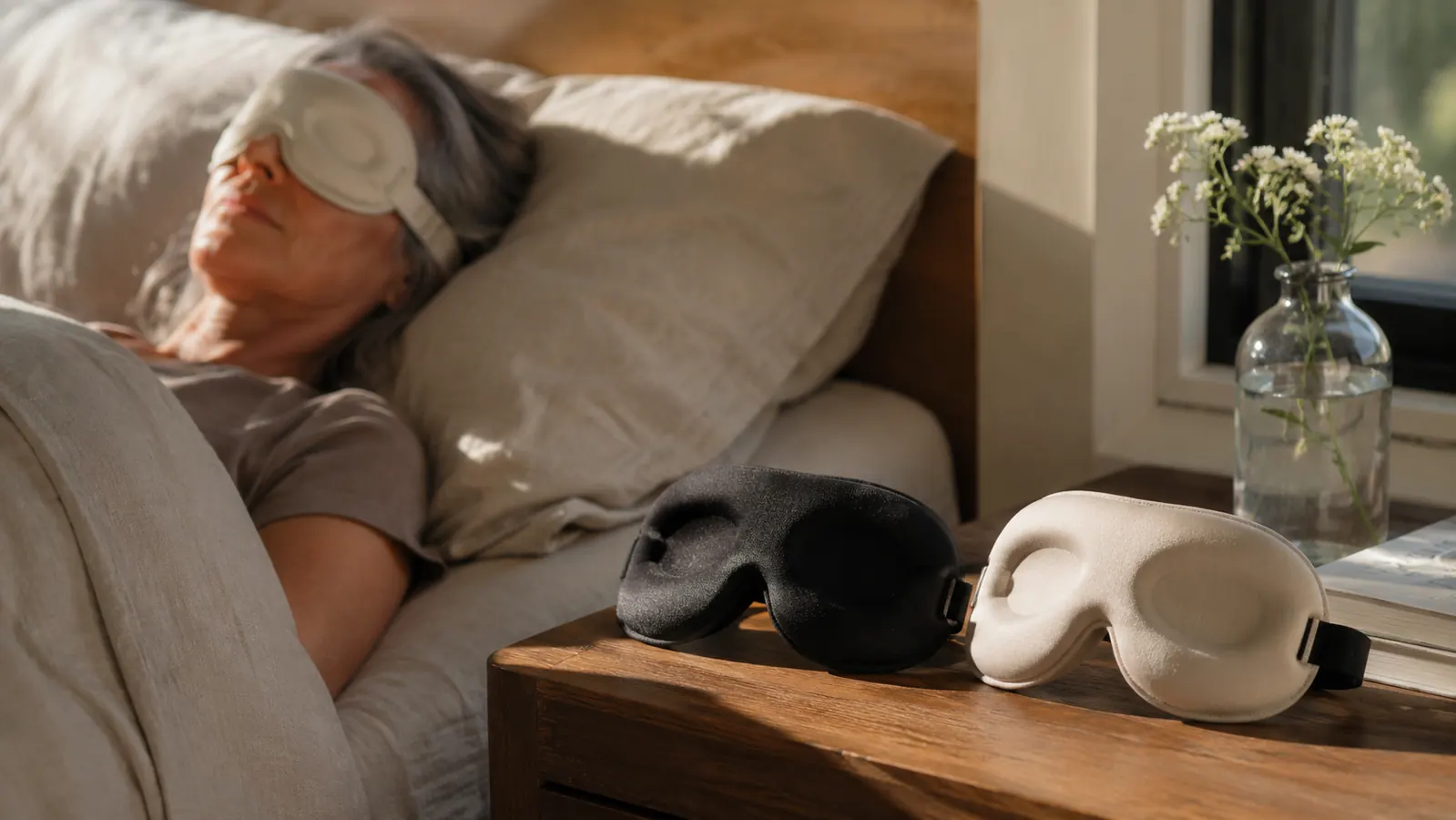 Two contoured sleep masks laid side by side on a nightstand in a sunlit second-floor bedroom